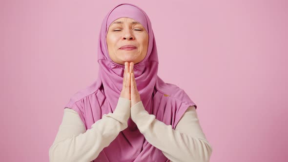 Emotional Middle Aged Muslim Woman in Traditional Headscarf Praying to God and Saying Please Making