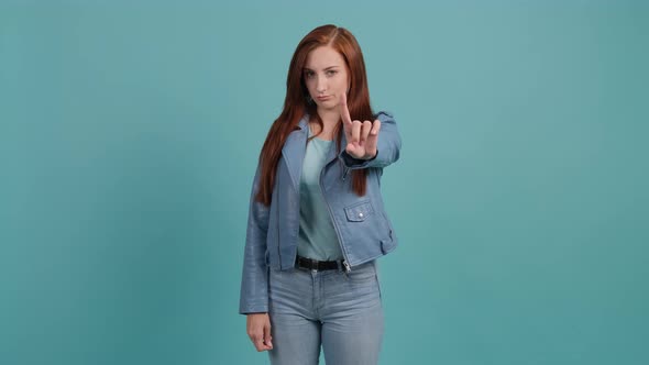 Portrait of Wonderful Woman Showing No with Her Finger on Turquoise Background.