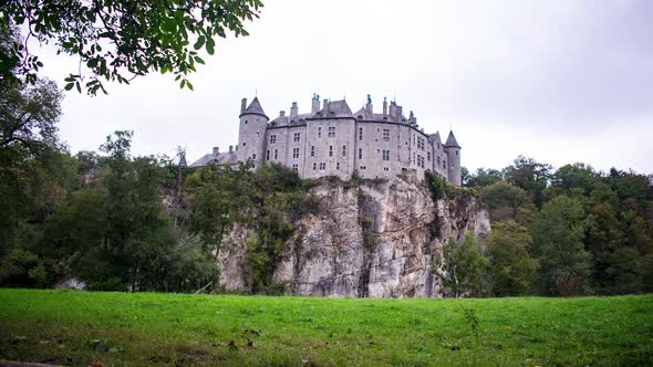 Castle on a cliff time lapse with clouds passing over the grassy pine tree fields in Dinant, Belgium