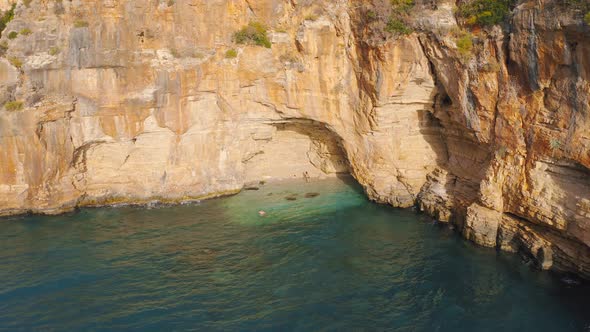 A Couple of Travelers Swims in a Hidden Cove with a Cave in Mountain on the Road From Demre To