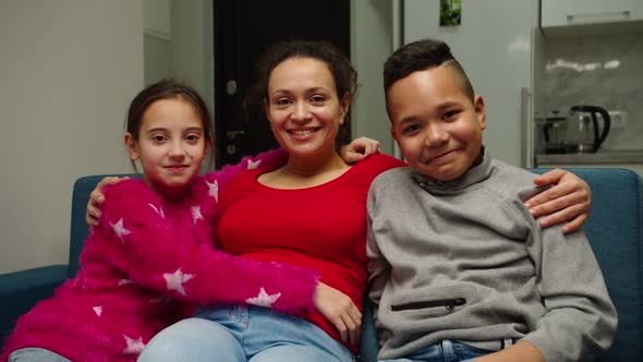 Happy Mother Cuddling Adorable Diverse Kids Indoors