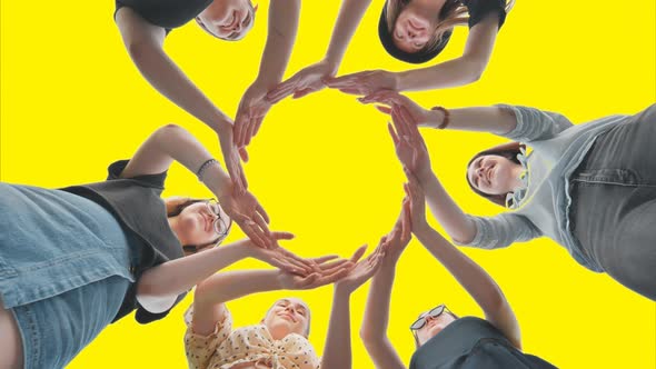 Friends Make a Circle with Their Palms Against a Yellow Background