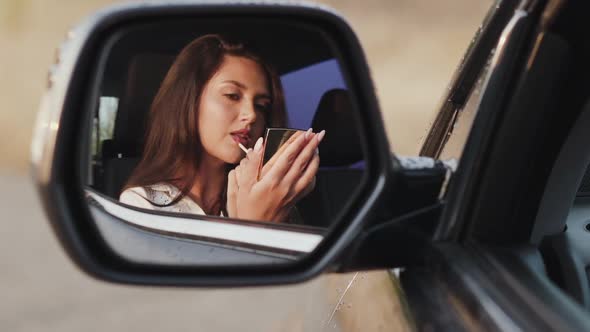 Reflection of Woman in Car Rear View Mirror Who Applying Lip Gloss and Smiling