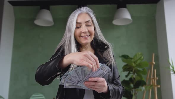 Beautiful Rich Mature Woman with Gray Hair Which Holding Dollars Bills Like as Handheld Fan