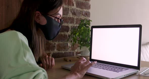 Woman in Mask Using Laptop at Home