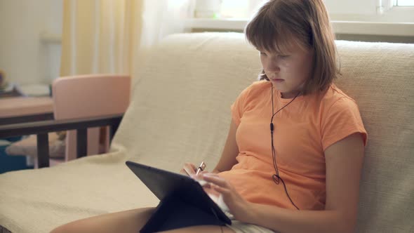 Teen Girl At Home On Couch Working In Tablet