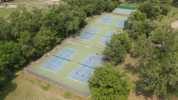 Group of tennis courts tucked into the trees in a park in Bismarck, North Dakota, on sunny day.
