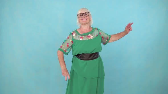 Fun Expressive and Energetic Old Woman Dancing on a Blue Background