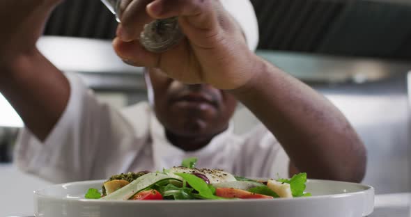 African american male chef garnishing dish in restaurant kitchen