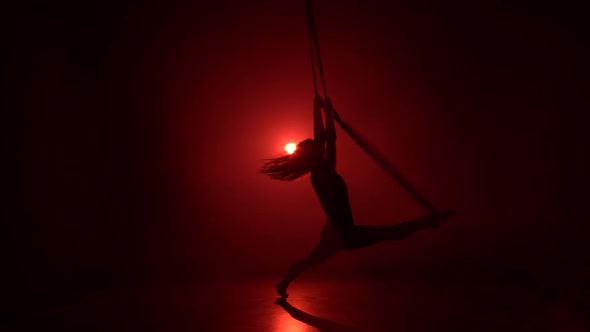 Aerial Acrobat in the Ring. A Young Girl Performs the Acrobatic Elements in the Air Ring on Red