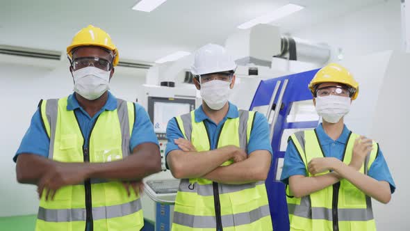 Group of diversity worker people wearing protective face mask in production factory due to covid 19.