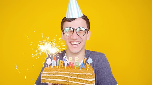 Happy Birthday Concept. Young Funny Man with a Cake o an Orange Background