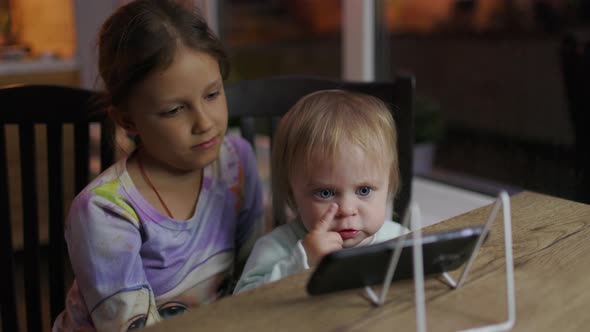 Little Children Together In The Evening Watching Video On Smartphone