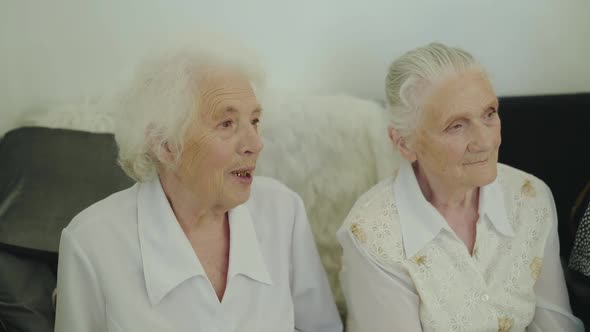 View of Two Greyhaired Cute Senior Women in White Blouses Talking in Room