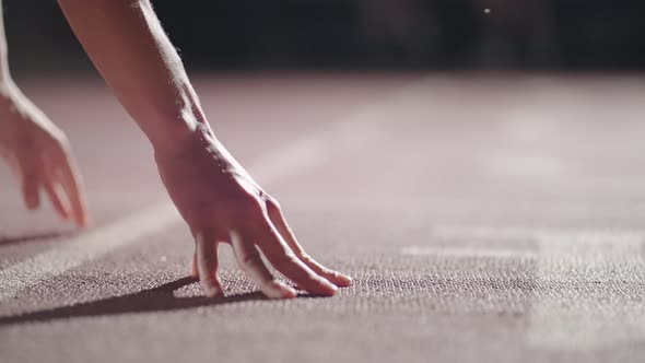 Woman Hand on Track As He Crouches in Starting Position at the Beginning of a Race