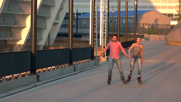 Couple Rollerblading and Holding Hands