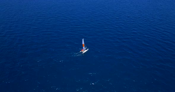 Aerial drone view of a man and woman sailing on a boat to a tropical island.