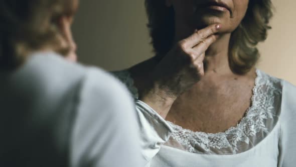 Senior Woman Looking at Her Reflection, Upset With Aging and Sagging Skin