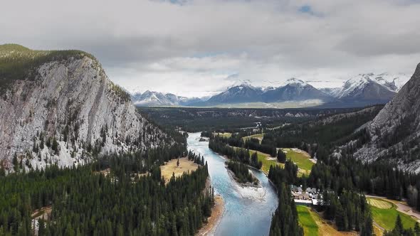 Drone rises and shoots Bow River and valley with mountains on the horizon in Banff, Alberta, Canada