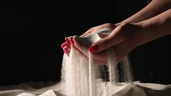 Women's Hands Picking Up Sand in Their Palms and Spilling Grains of Sand Through Their Fingers