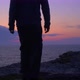 Young Man Walks to a Rocky Sea Shore to Wait for the Sunrise. Stands Upright. Silhouette - VideoHive Item for Sale