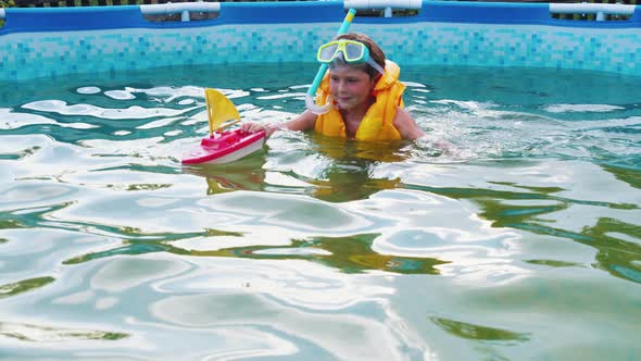 A Little Boy Swimming Playing with a Toy Boat in the Inflatable Pool