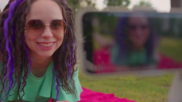 A female blogger shoots a video on a camera on a tripod on a sunny summer day