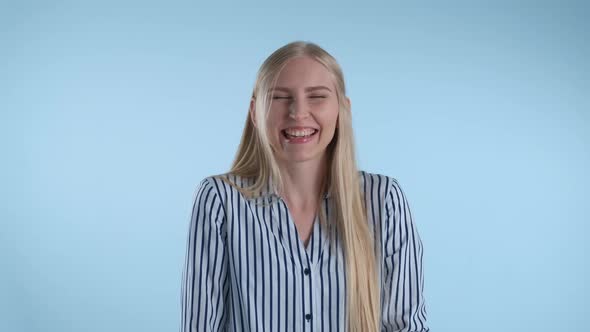 Happy Young Lady Bursting in Laughter on Blue Background