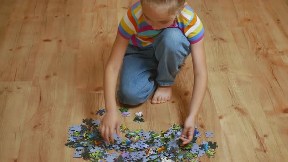 A Beautiful Girl Collects Puzzle Puzzles Sitting on a Wooden Floor