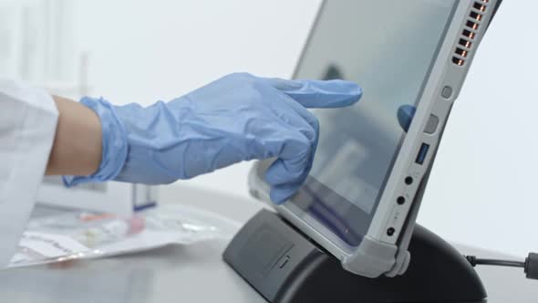 Lab technician using touchscreen processing covid-19 test kits