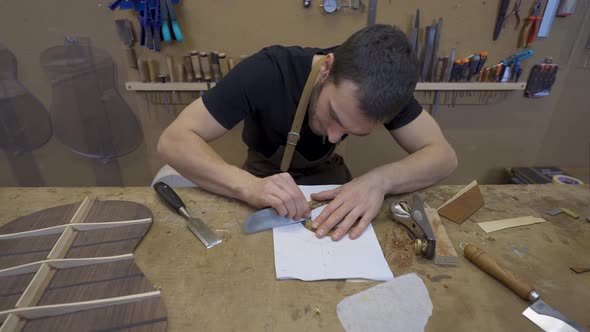 Craftsman flattening wooden piece with scraper in workroom