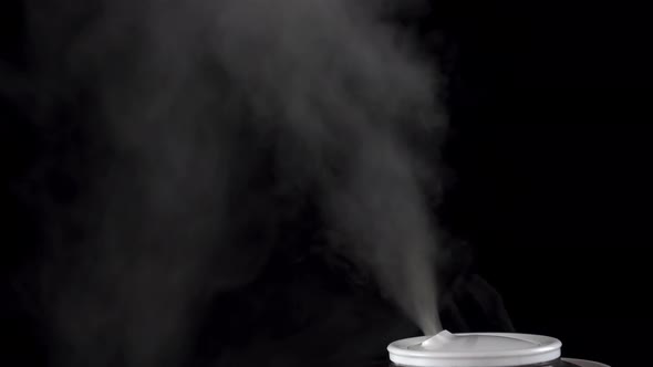 An Ultrasonic Humidifier Humidifies a Room with a Strong Stream of Steam on an Isolated Black