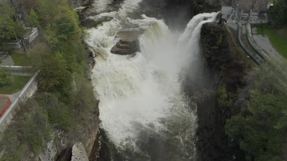 Drone shot, flying forward and panning down, over a big waterfall.