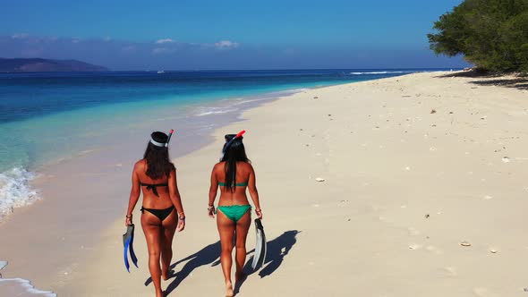 Pretty fun women on holiday in the sun on beach on sunny blue and white sand 4K background