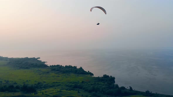 Sailwing Is Flying High in the Sky Above the Water and Fields