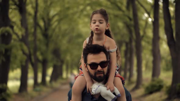 Happy Family Father With Child Girl Leisure Outdoors. Daughter Sitting On Father Neck. Carefree Dad.