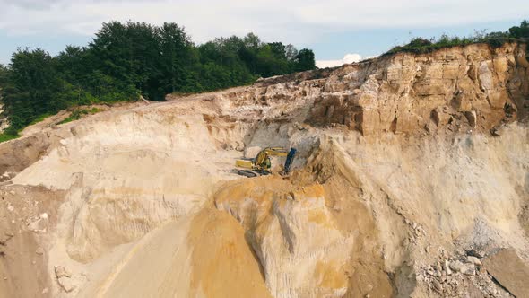 Excavator Working in a Sand Quarry and Extracting Sand. An Excavator Picks Up Sand with a Bucket and