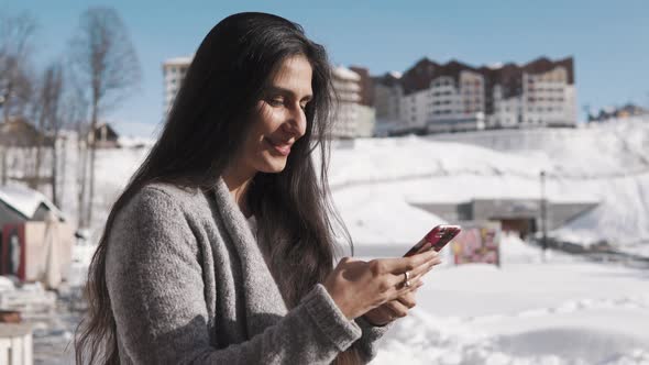 Adult Brunette Lady Is Answering on Message in Her Phone, Outdoors in Winter Day