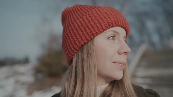 Girl in an Orange Hat in Winter Looks Around and Smiles, Happy Woman