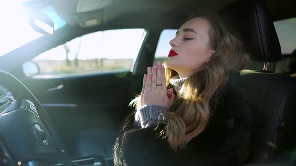 Slim Desperate Young Woman Praying Sitting in Car