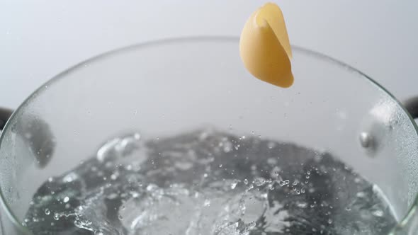 Camera follows cooking shell noodles in boiling water. Slow Motion.