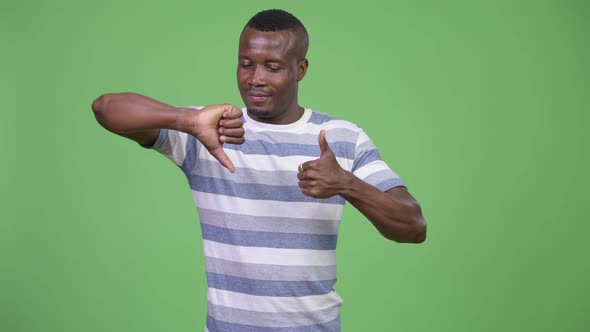 Young African Man Choosing Between Thumbs Up or Thumbs Down