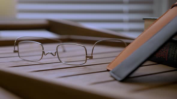 A Close Up Look at the Glasses Lying Near Books on the Wood Table