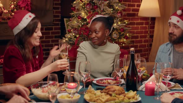 Cheerful Diverse Women Discussing at Christmas Dinner While Enjoying Food and Champagne