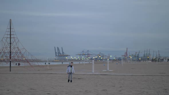 Young Boy Walking on the Beach on a Cold Day