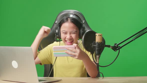 Asian Kid Girl Playing Video Game With Phone Then Celebrating While Live Stream On Green Screen