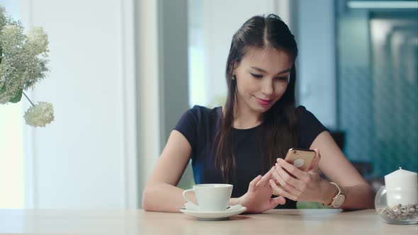 Happy Female Watching Her Photos on Cell Phone in Coffee Shop