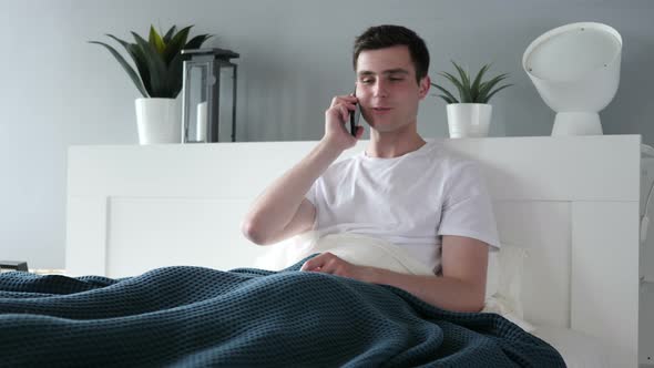 Man Talking on Phone While Lying in Bed