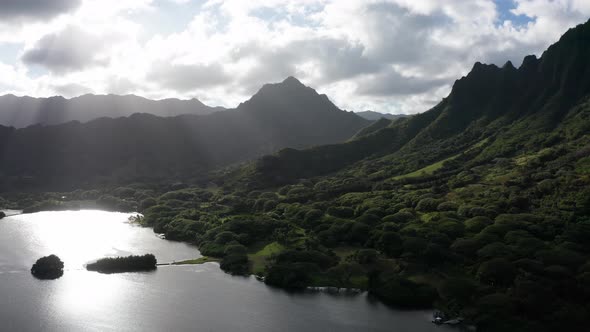 Dolly aerial shot of an ancient fishpond and coastal mountain ridge on the island of O'ahu, Hawaii.