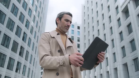 Close up handsome businessman using his tablet computer - scrolling, taping and texting walking